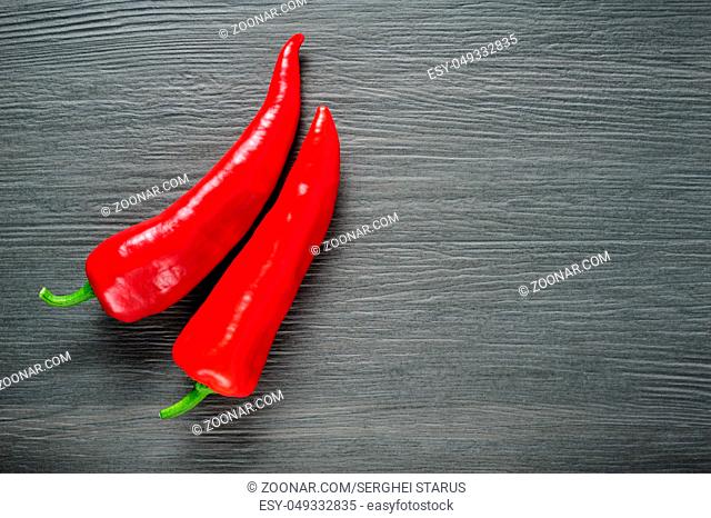 Two ripe sweet red Kapia peppers on dark shale stone background