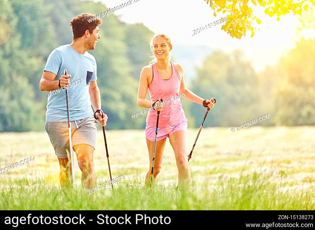 Glückliches junges Paar beim Wandern mit Nordic Walking Stöcken