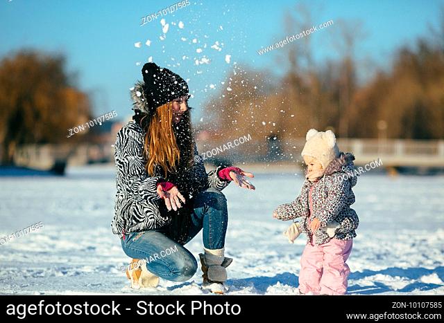 happy family mother and baby girl daughter playing in winter outdoors in the snow