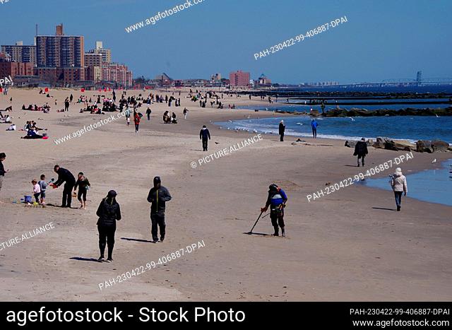 10 April 2023, USA, New York: Equipped with a metal detector, rubber boots, a sieve and two plastic containers, George Pessard is out on the beach at Coney...