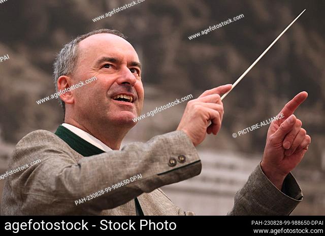 28 August 2023, Bavaria, Miltenberg: Hubert Aiwanger, chairman of the Free Voters, conducts the town band on stage at the Craftsmen's Day at the Michaelmas Fair