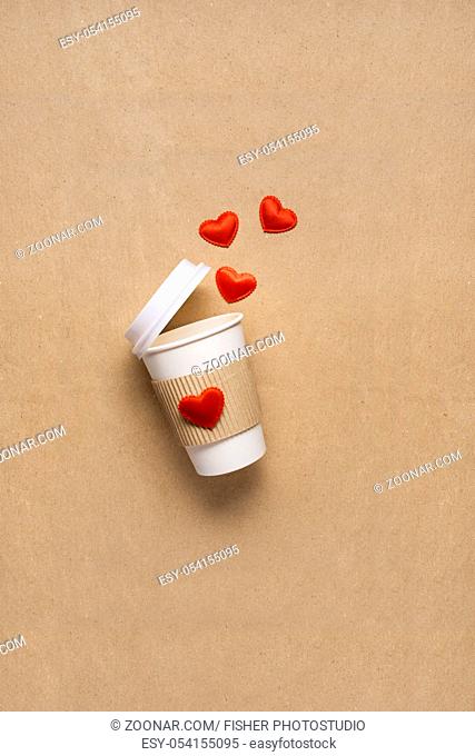 Creative concept photo of take away coffee cup with hearts on brown background
