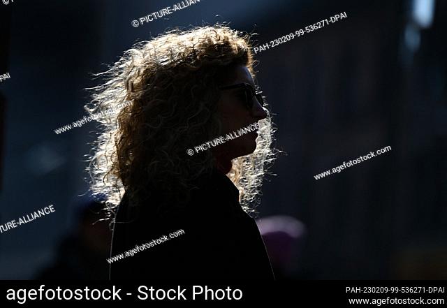09 February 2023, Hesse, Frankfurt/Main: The curly hair of a woman waiting on a street downtown glows in the backlight. Photo: Arne Dedert/dpa