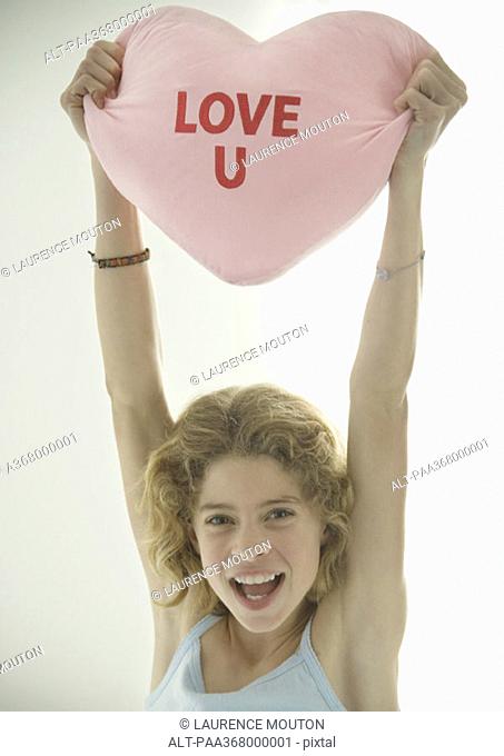 Preteen girl holding up heart shaped pillow