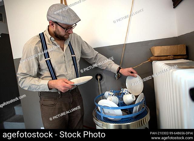 18 February 2021, North Rhine-Westphalia, Datteln: Kevin Nikodem fills his 1950s dishwasher in his home. Nikodem lives like he did in the 50s