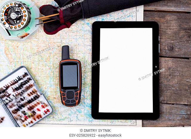 mockup intend to fishing journey with fly-fishing tackles and gps navigator and pad on paper map background