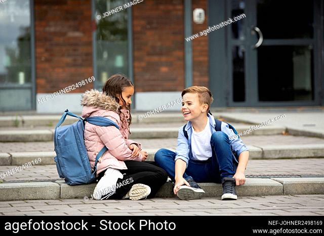 Boy and girl talking in front of school