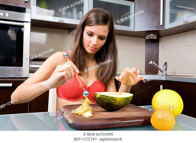 Woman in her underwear preparing a melon for juice
