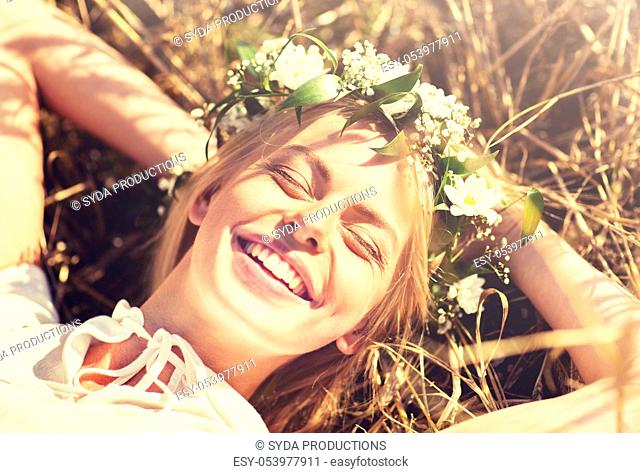 happy woman in wreath of flowers lying on straw