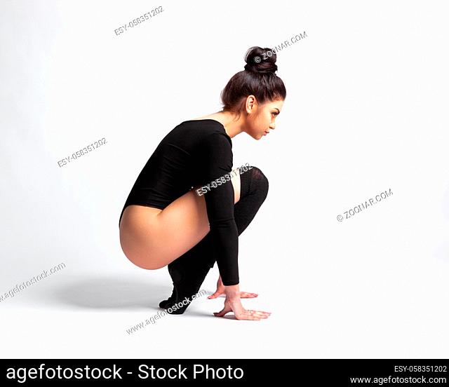 Beautiful sexy brunette in a black body and golf over a gray background. Concept grace, flexibility, dance and plasticity