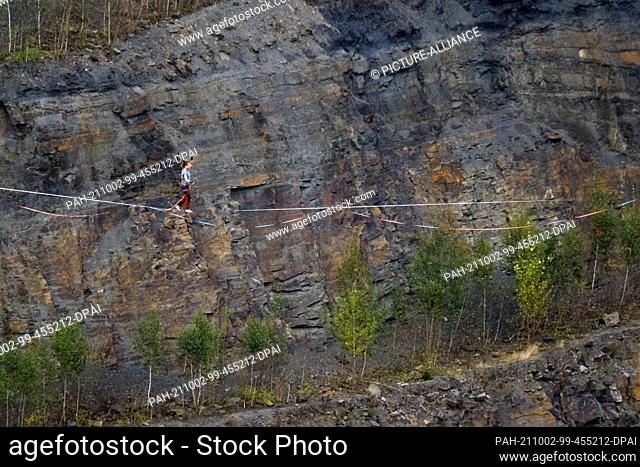 02 October 2021, Lower Saxony, Osnabrück: A man walks across a slackline. Germany's best slackliners want to conquer the Piesberg Quarry on a 350-meter course