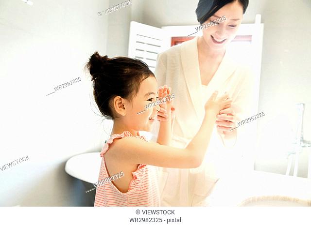 Little girl playing with mother at bathroom