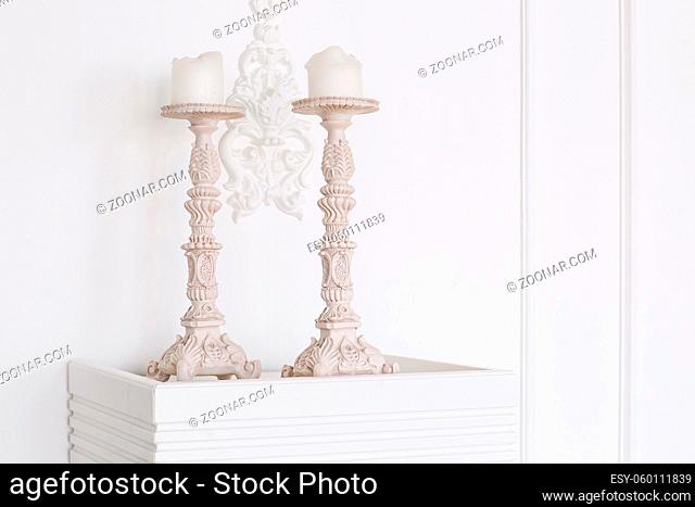 White antique candlesticks with candles close up. stucco wall