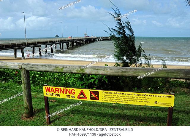 The coast and seaside resort Palm Cove in the tropical northeast of Australia - a sign on the beach indicates the danger of crocodiles and bathing prohibition...