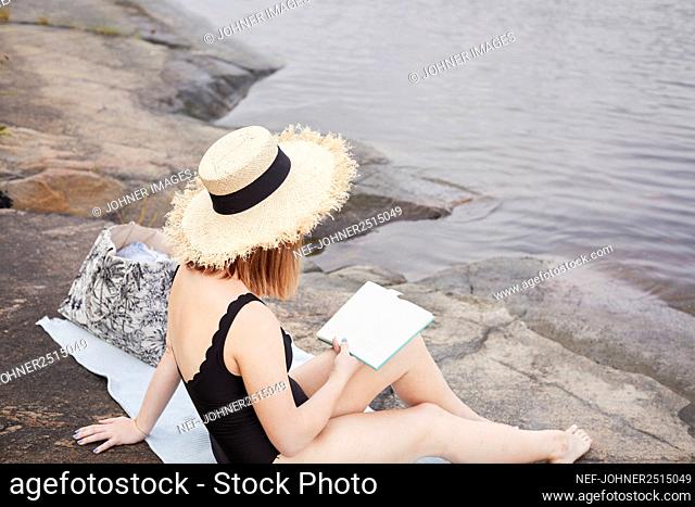 Woman reading book at lakeside