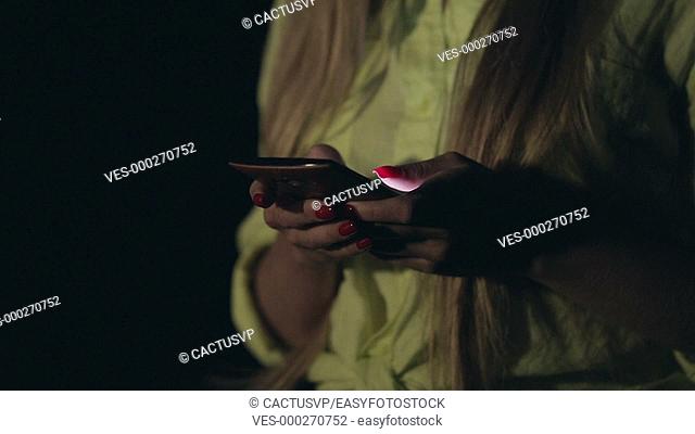 Young sensual woman using smartphone at night