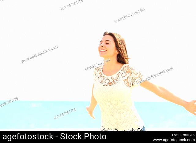 Happy woman breathing deep fresh air enjoying wind on the beach