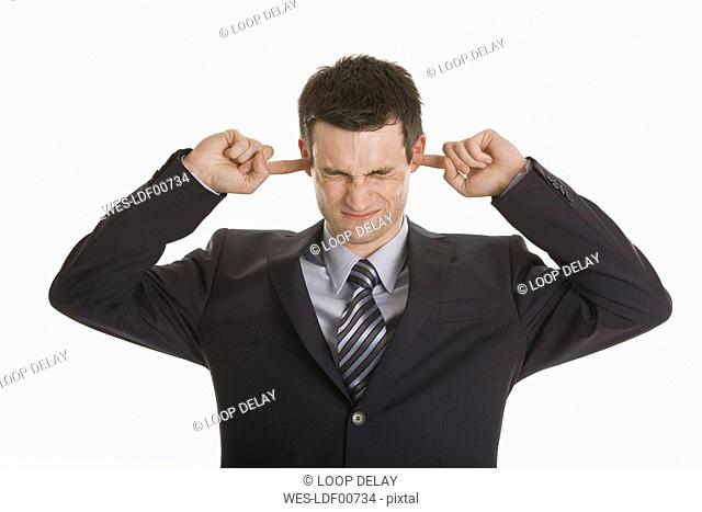 Businessman closing his ears with fingers