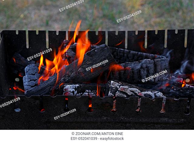 Blaze of bonfire, wood fire flame heat spires burning in bbq grill fireplace with smoke close up