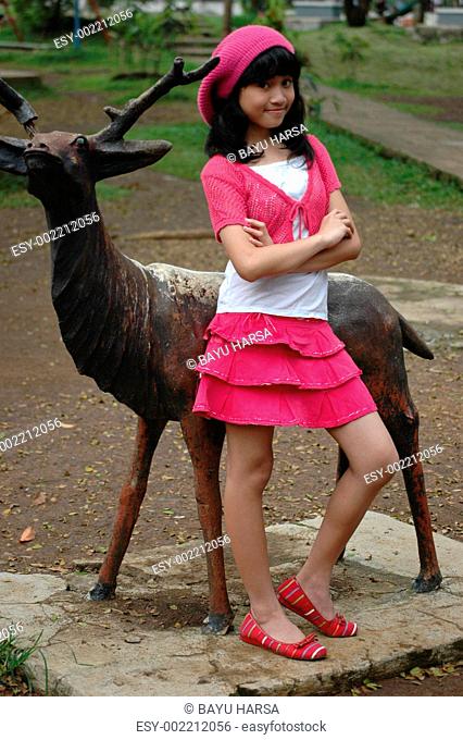 cute girl stand up beside deer statue