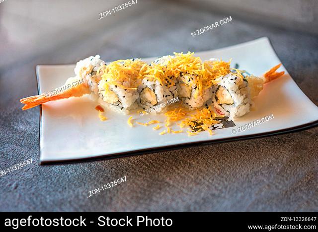 shrips sushi served on rectangular white plate on dark gray stone background