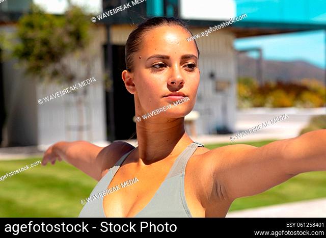 Close up of caucasian young woman practicing yoga and meditating near the pool