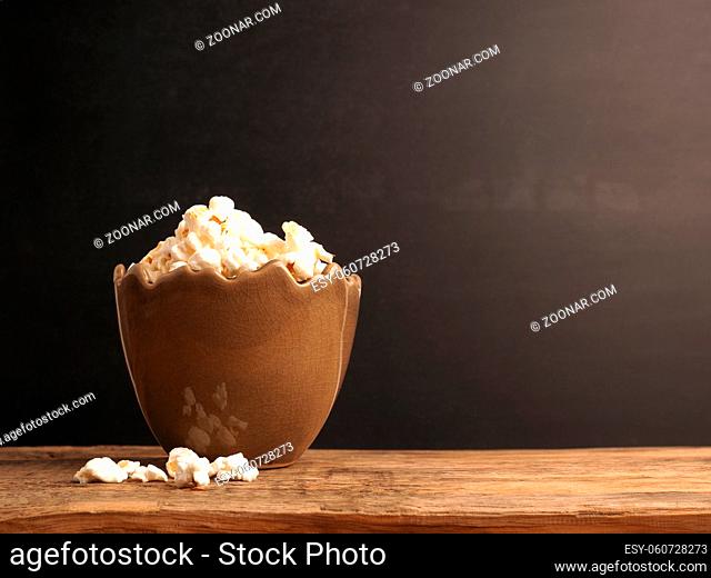 Egg-shaped vase filled with popcorn against a dark blackboard, stay at home Easter concept, television or movie concept