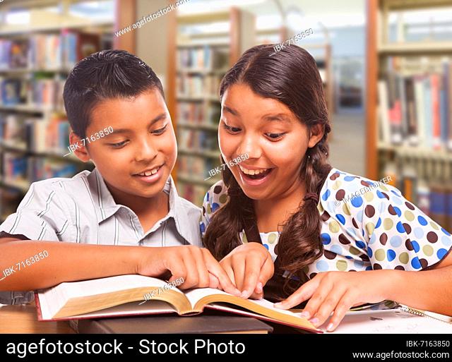 Hispanic boy and girl having fun studying together in the library