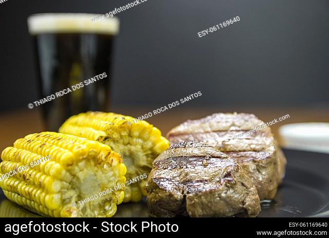 Delicious filet mignon close-up with roasted corn and glass of beer