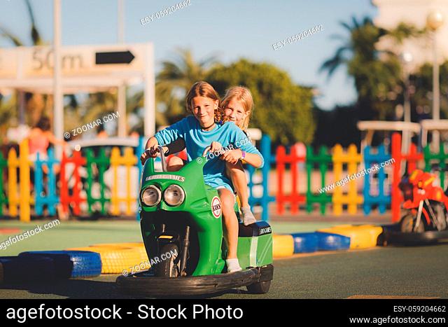 Young girls riding on an electric toy motorbike on a sunny afternoon