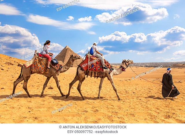 Tourists riding camels near the Pyramids of Giza