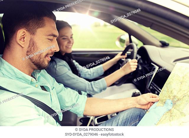 happy man and woman with road map driving in car