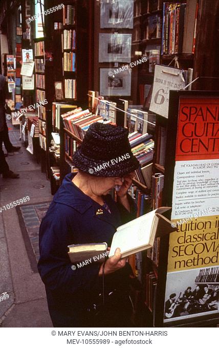 London Street Scene -- a woman peruses a book on the pavement outside a book shop