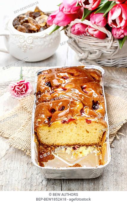 Fruit cake in rectangular pan. Bouquet of pink tulips in the background