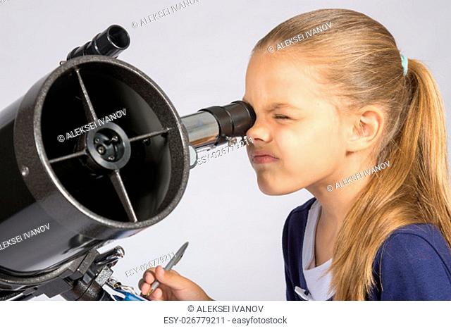 The young astronomer looks through the eyepiece of the telescope and record results