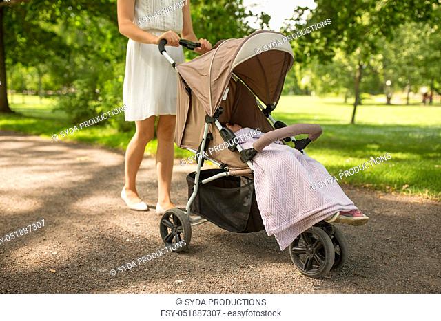 mother with child in stroller walking at park