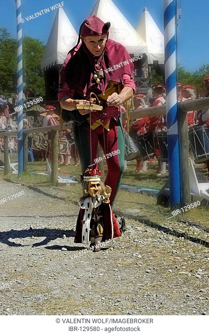 Puppet player in mediaeval medieval costume holding little marionette king , knight festival Kaltenberger Ritterspiele, Kaltenberg, Upper Bavaria, Germany
