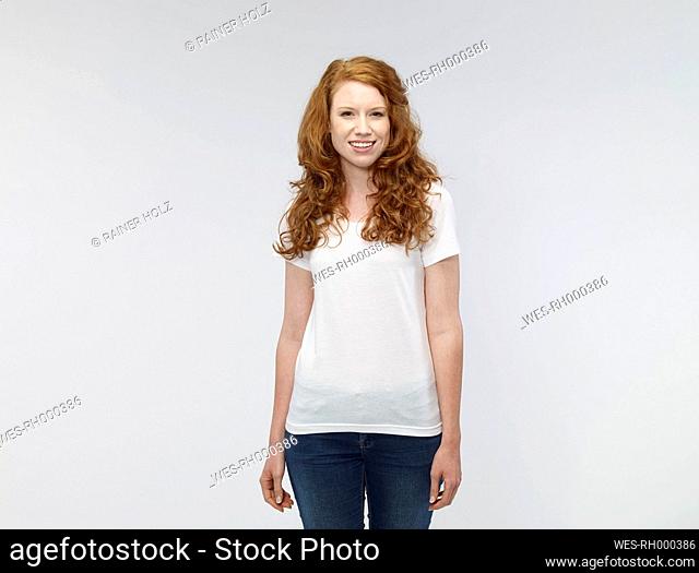 Portrait of smiling young woman in front of white background