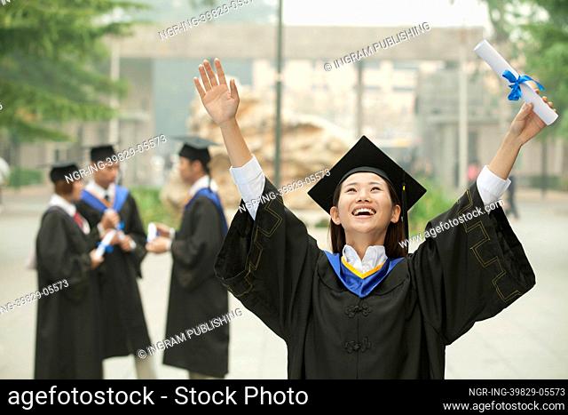 Young Female University Graduate, Arms Raised in the Air with Diploma