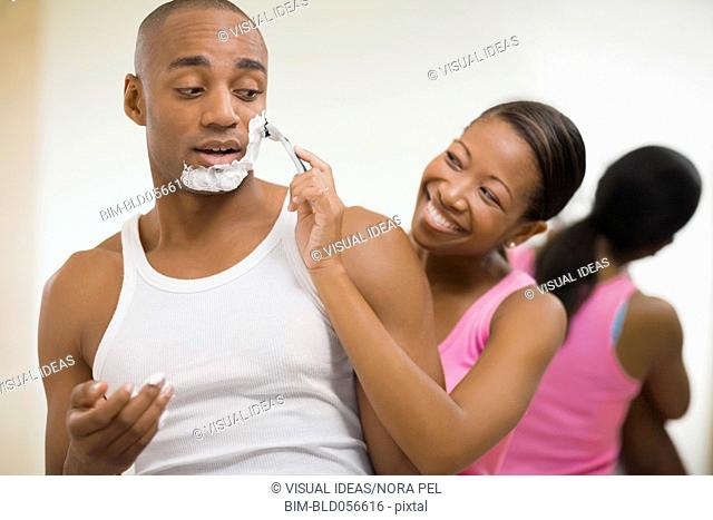 African woman helping husband shave