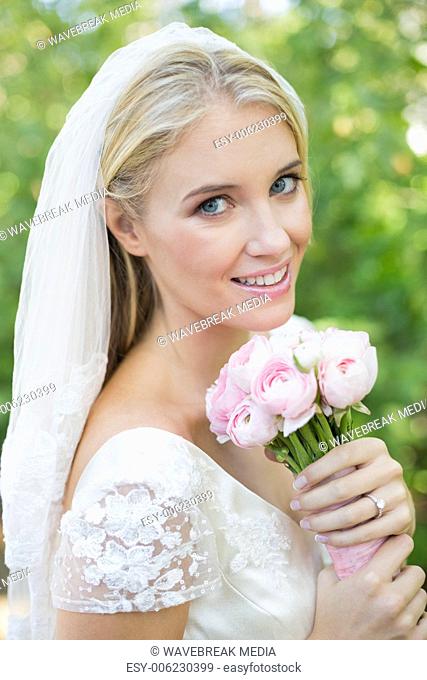 Happy bride holding her bouquet smiling at camera