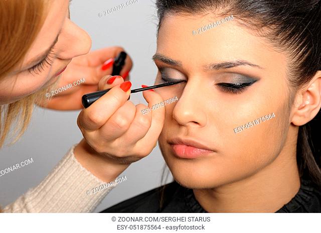 Beautiful brunette portrait, applying perfect makeup to her face