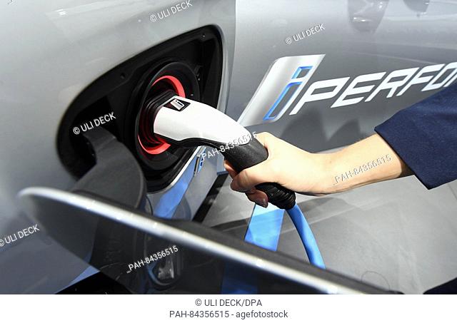 A woman using a Typ 2 charging plug for a BMW 330e, a so-called 'Plug-in-Hybrid', during the first press day at the Paris Motor Show (Mondial de l'Automobile)...