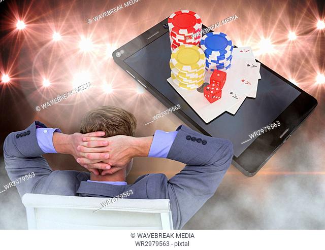 Man seated relaxed looking at phone with 3d poker chips and playing cards