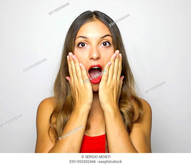Surprised woman holds her cheeks by hands. Beautiful woman holding her face with open mouth looking at the camera on white background
