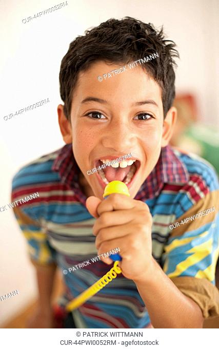 Smiling boy playing with toy microphone