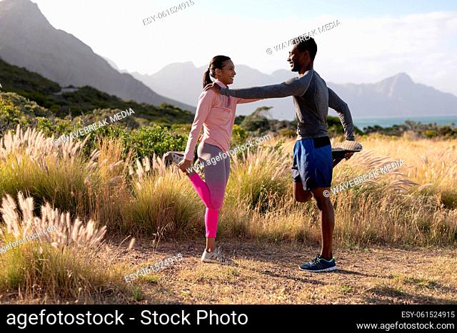 Fit african american couple in sportswear stretching in tall grass