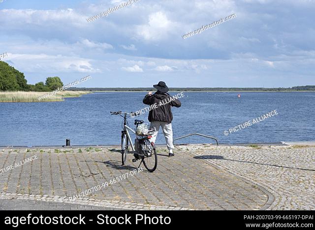 05 June 2020, Mecklenburg-Western Pomerania, Hiddensee: A man is standing at the harbour basin and practices Qi Gong exercises