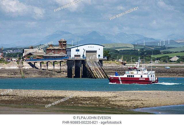 'Assister' offshore tug and supply ship entering port through Piel Channel, past Roa Island and RNLI lifeboat station, Barrow-in-Furness, Cumbria, England, July