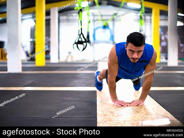 Young strong man doing pushups at cross fitness gym